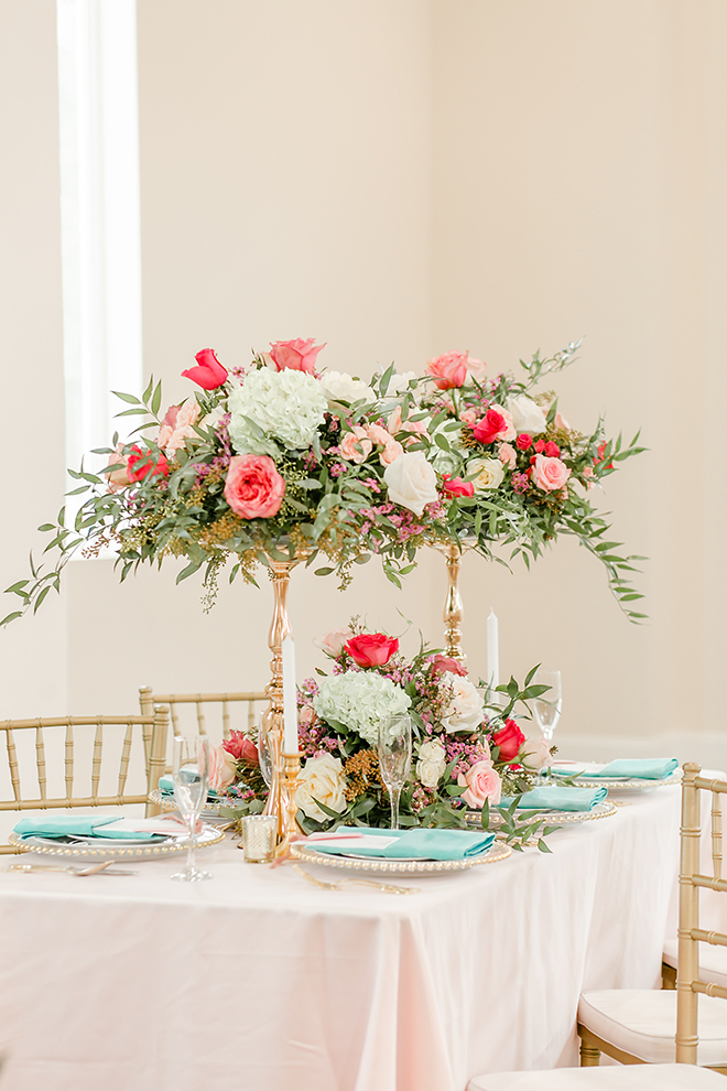 aqua napkins, pop of color, wedding theme, tall centerpieces, gold vase, gold flower stand, gold beaded charger, pink table linens, gold chiavari chairs