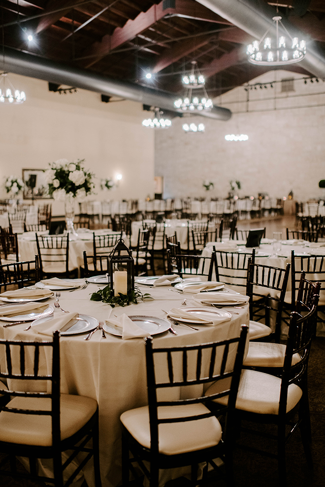 Ballroom at Briscoe Manor decorated with round banquet tables, ivory linens and tall white floral centerpieces. 