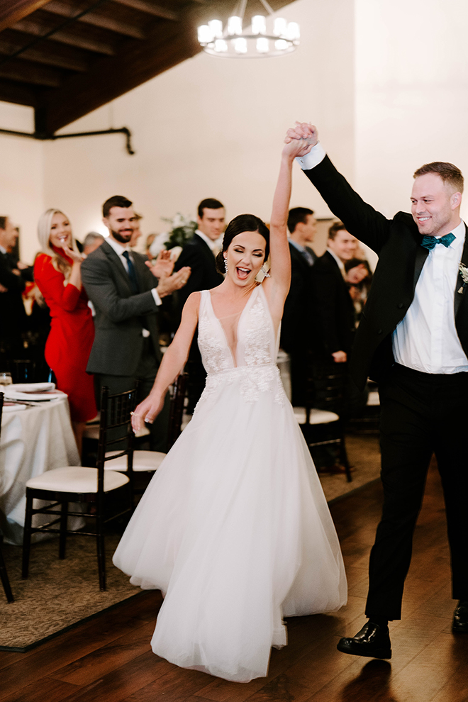 Bride and groom holds hands while entering the ballroom at Briscoe Manor after their chapel wedding ceremony. 