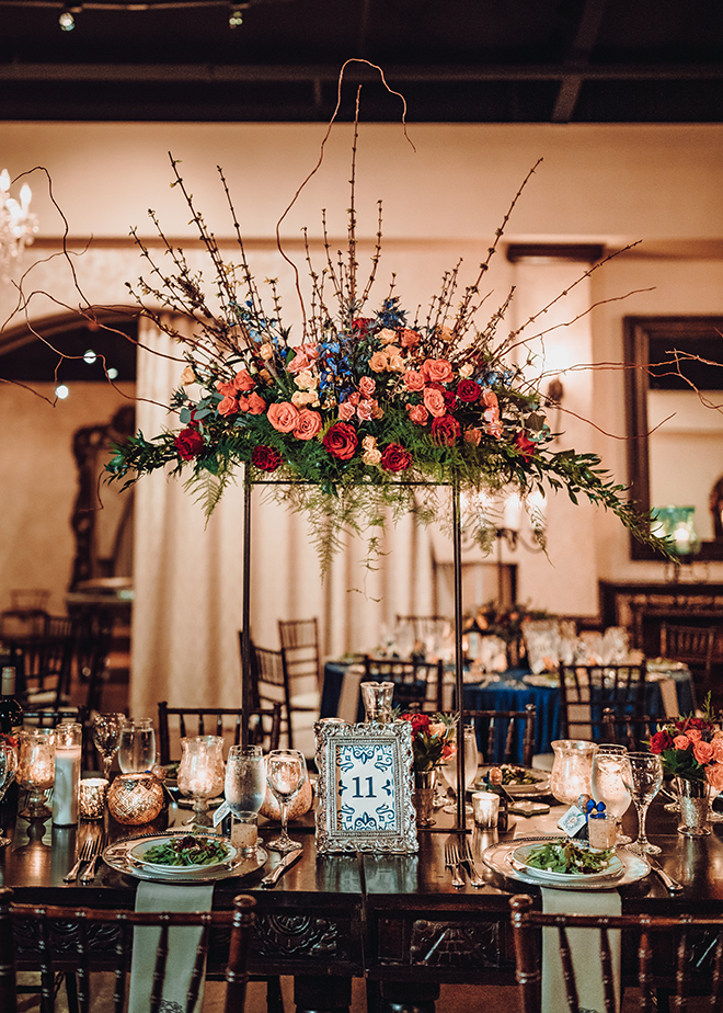 reception decor, madera estates, spanish-inspired wedding, chandeliers, candles, tall floral centerpieces, red, orange, yellow, roses, greenery, table setting, wedding table