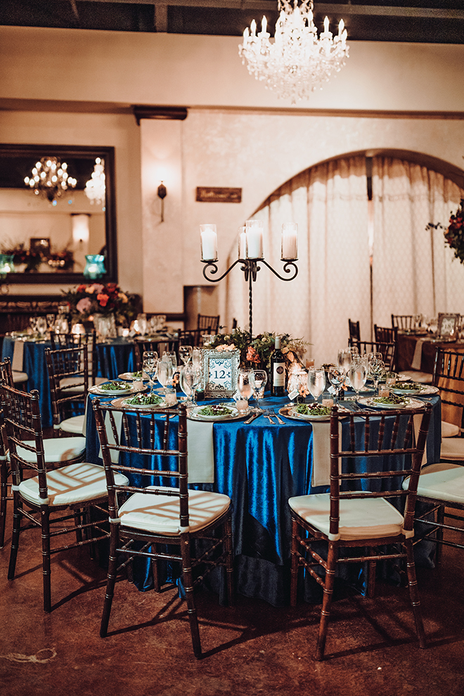 reception decor, madera estates, blue linens, spanish-inspired wedding, chandeliers, candle centerpieces, greenery, table setting, wedding table