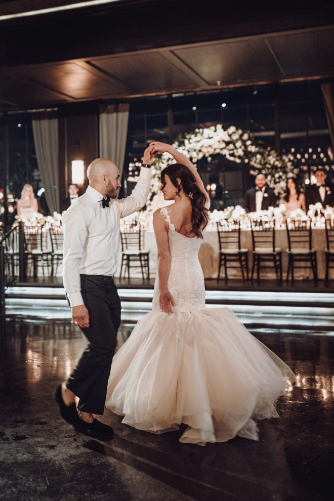 Bride and groom dancing for first dance, groom is twirling bride revealing the back of brides dress