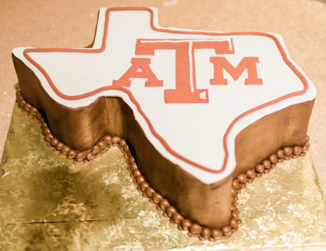 Grooms cake shaped like the state of Texas with burnt orange lettering with the abbreviation for Texas ATM University