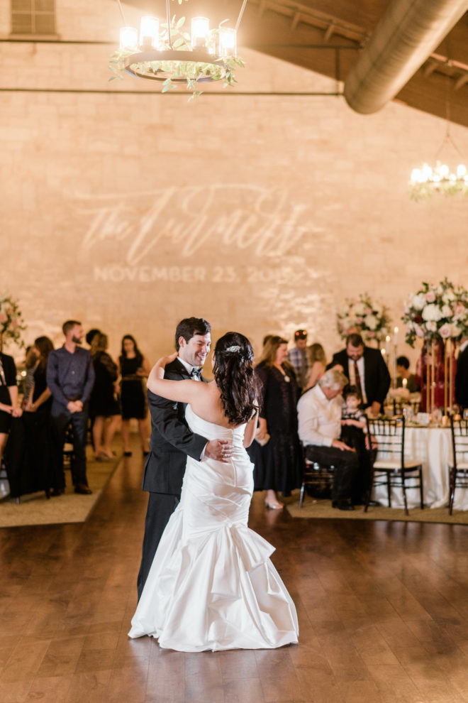 Couple dancing at reception in front of personalized name light wall. 