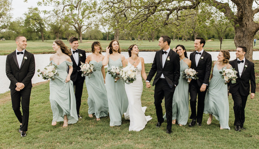 Bride, groom and co-ed wedding party members smile and laugh at destination wedding venue, Hyatt Regency Lost Pines Resort and Spa. 