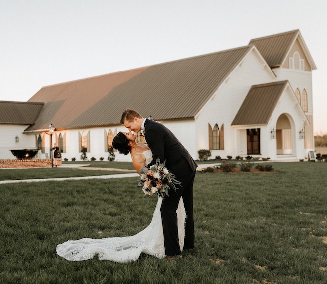 Bride and groom kissing in front of Deep In The Heart wedding venue. 