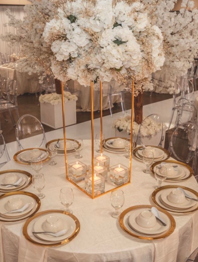 Wedding guest table decorated in gold and ivory placesettings with lush blooming floral centerpiece with beige, white and ivory florals by Mod Effect Events 