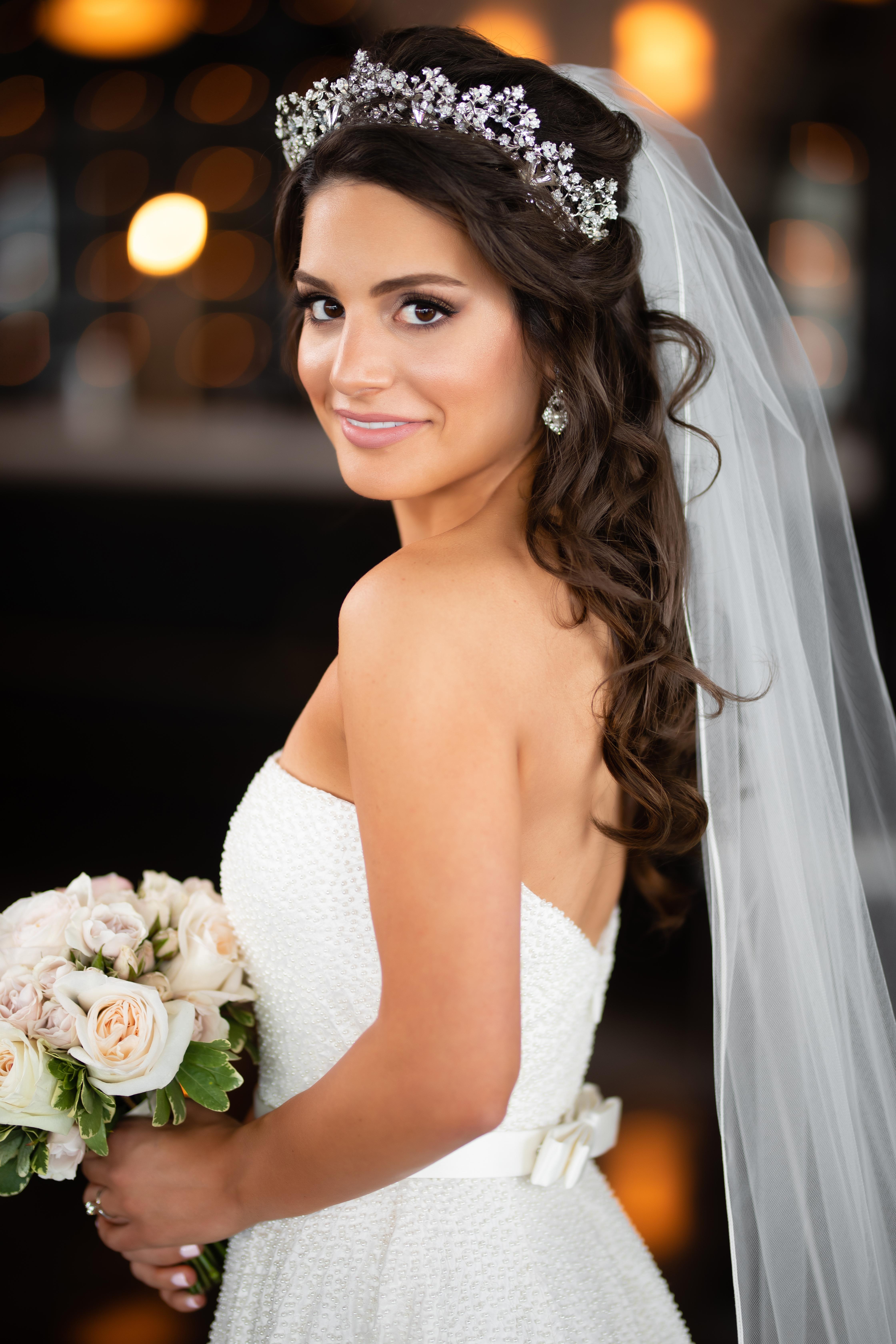 Bride with crown and long bridal veil with a classic white dress and ivory rose bouquet. 