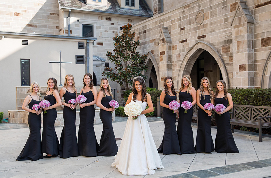 Bridesmaids hold bouquets that match the lavender, violet, and ivory wedding theme.