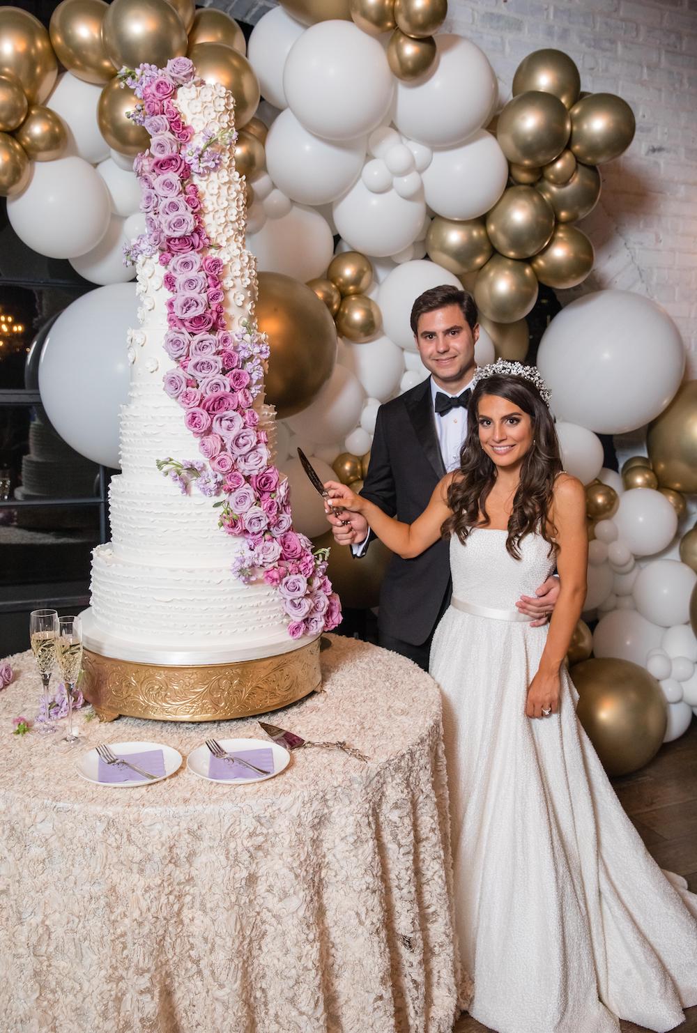 Purple flowers cascade down a seven-tier traditional wedding cake.