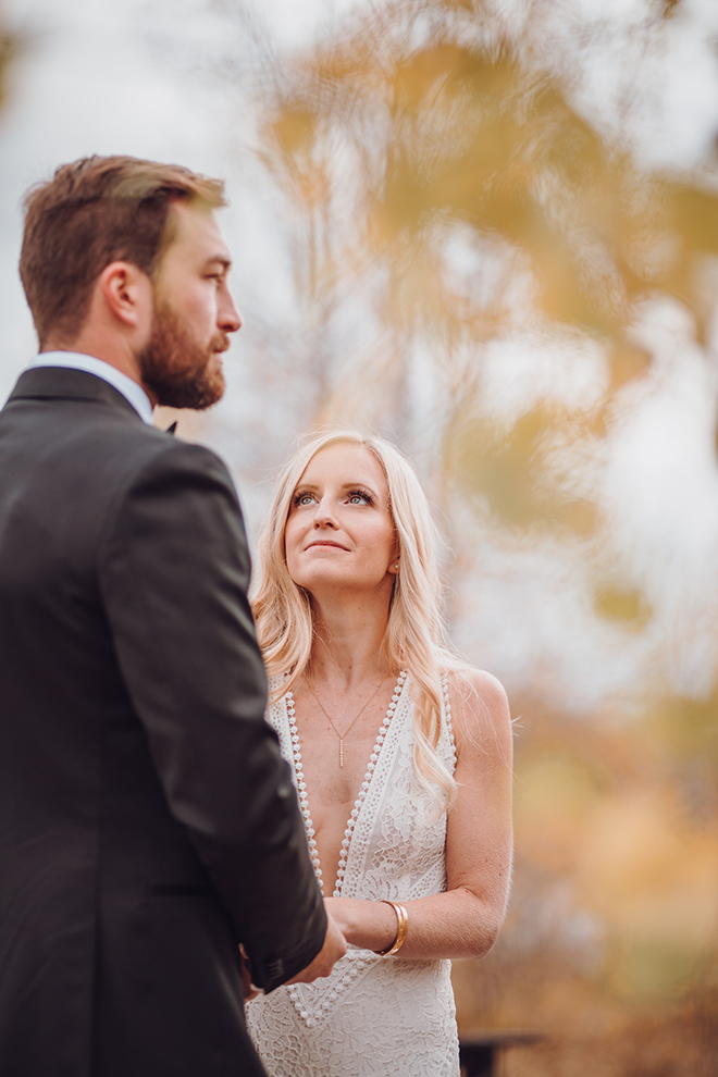 A smiling blonde bride looks up at a groom during their alfresco wedding ceremony in Jackson Hole, Wyoming. 