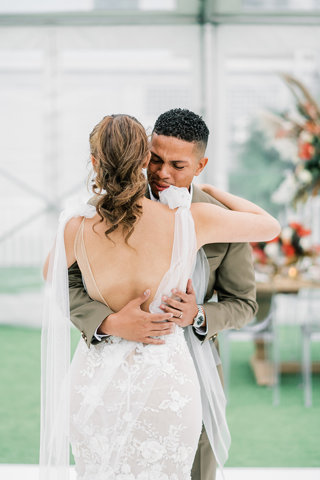 An groom is overcome with emotion during the first look, as he embraces his bride wearing a low-back Galia Lahav dress.