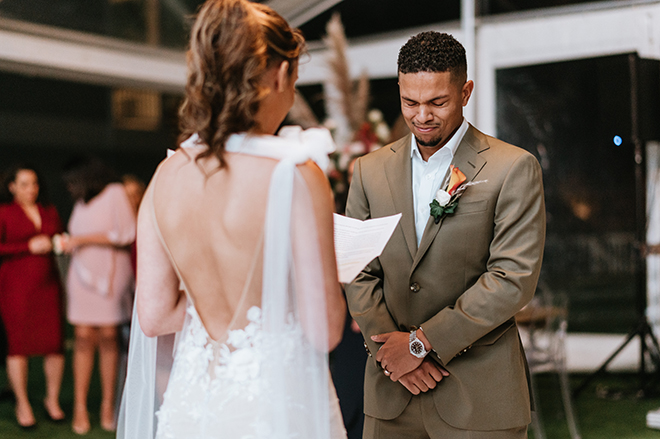 The groom gets teary eyed as his bride reads him her heartfelt custom vows.