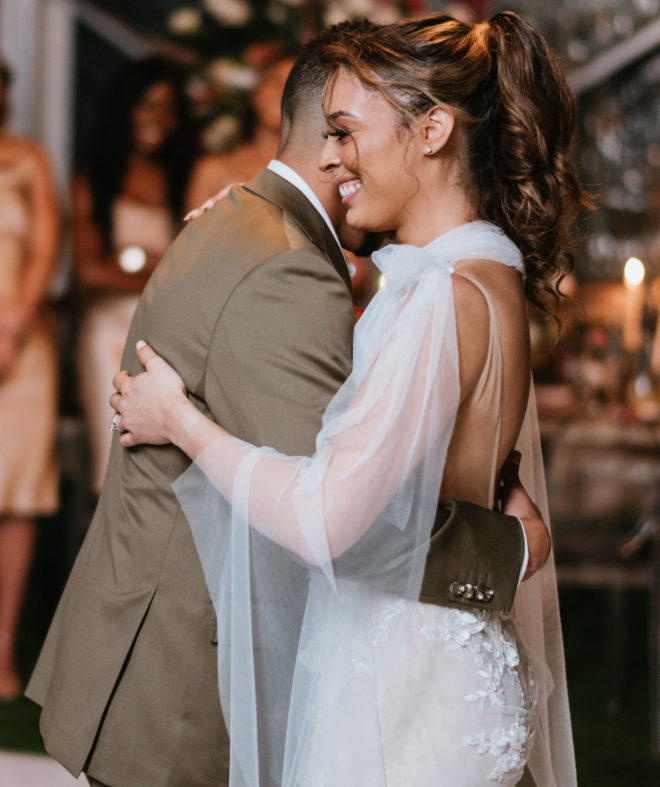 Groom and bride dancing closely while bride smiles during a tented wedding reception on Galveston Bay