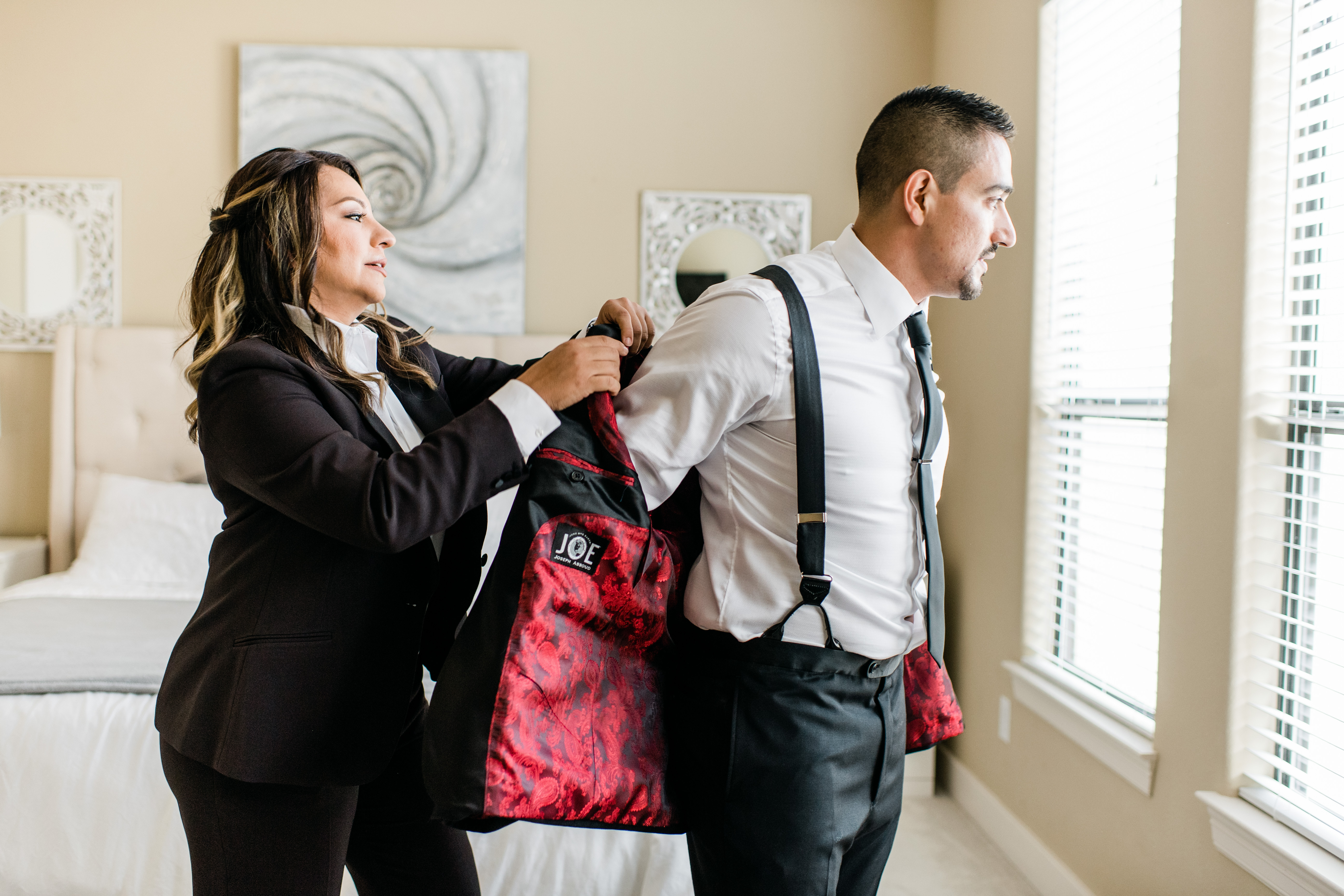 The groom's sister helps him put on his suit jacket.