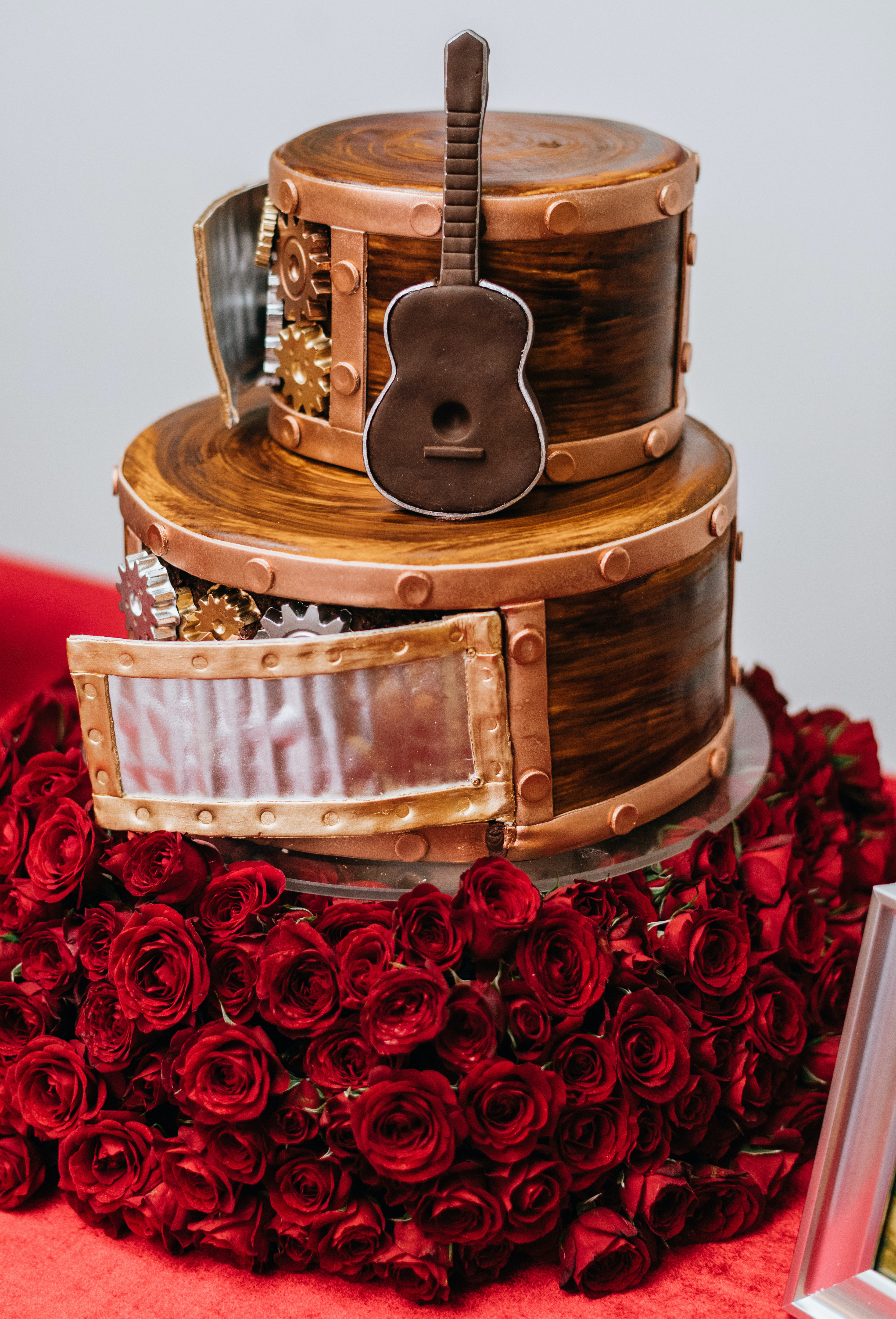 The groom's cake has a guitar on it and red roses surrounding the base.