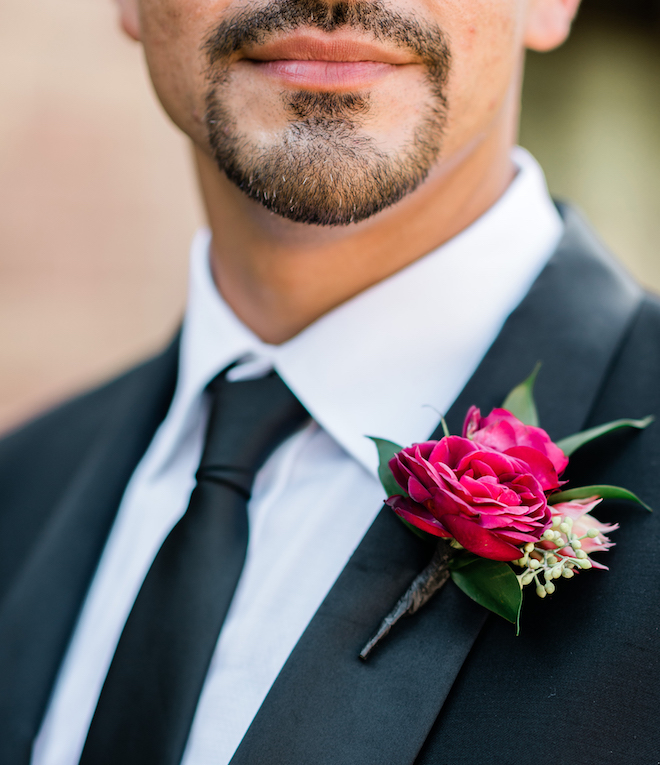 An up-close photo of the groom's ruby red boutonniere.