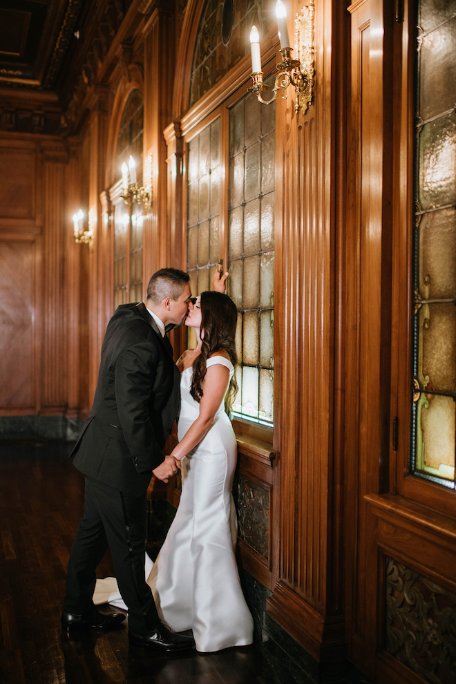 The bride and groom kiss in a romantically candle-lit hallway