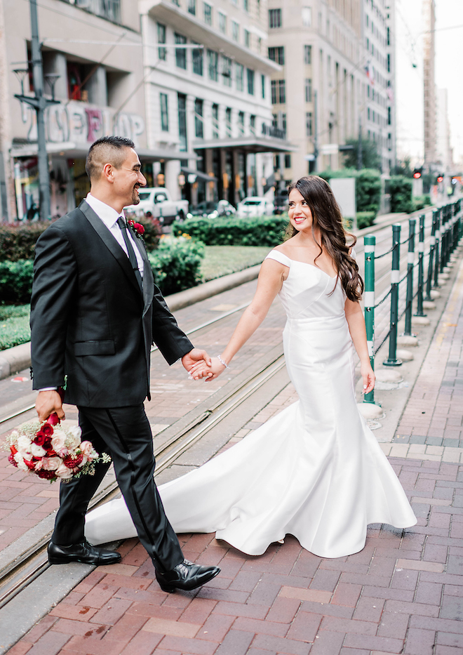 Bride and Groom holding hands walking through the city.