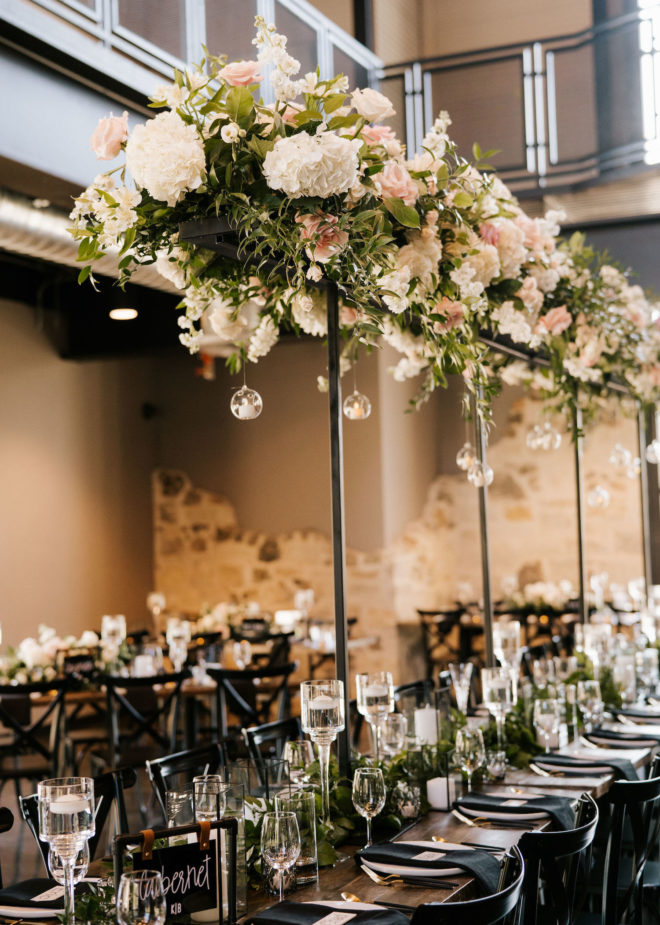 Long farmhouse table with tall hydrangea, rose and greenery floral installation inside of wedding venue, Park 31, in Spring Branch, Texas in the Texas Hill Country. 