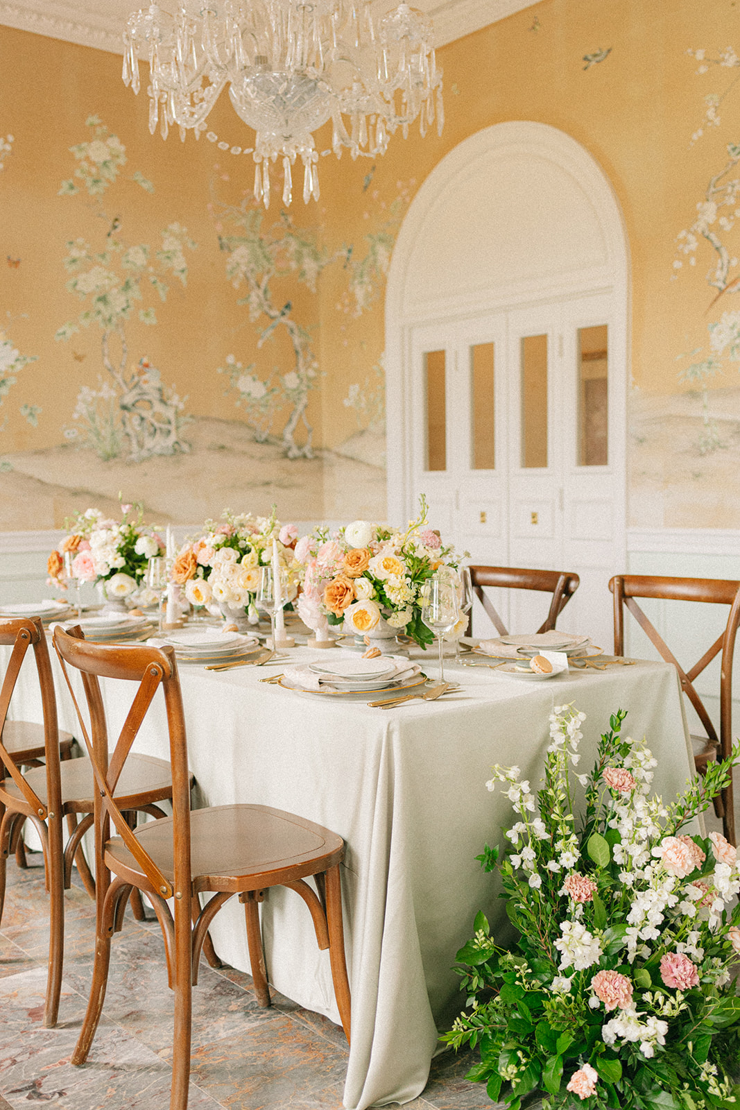 Reception room at The Mansion at ColoVista for the artfully curated styled shoot. Flowers are covering the table and there is a crystal chandelier hanging above the dining table.