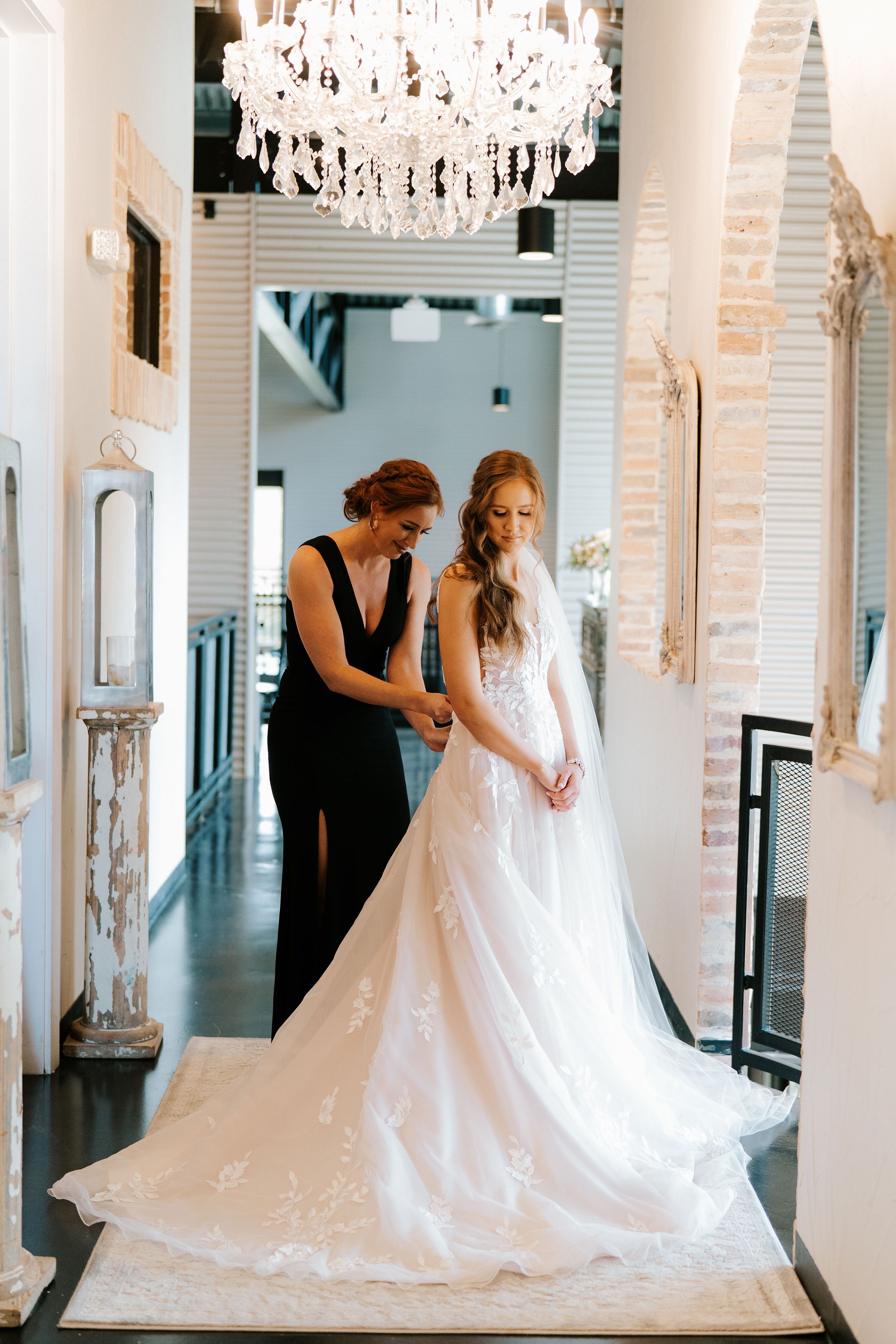 A bridesmaid finishes buttoning her friend's Essence of Australia wedding dress before her industrial chic wedding.