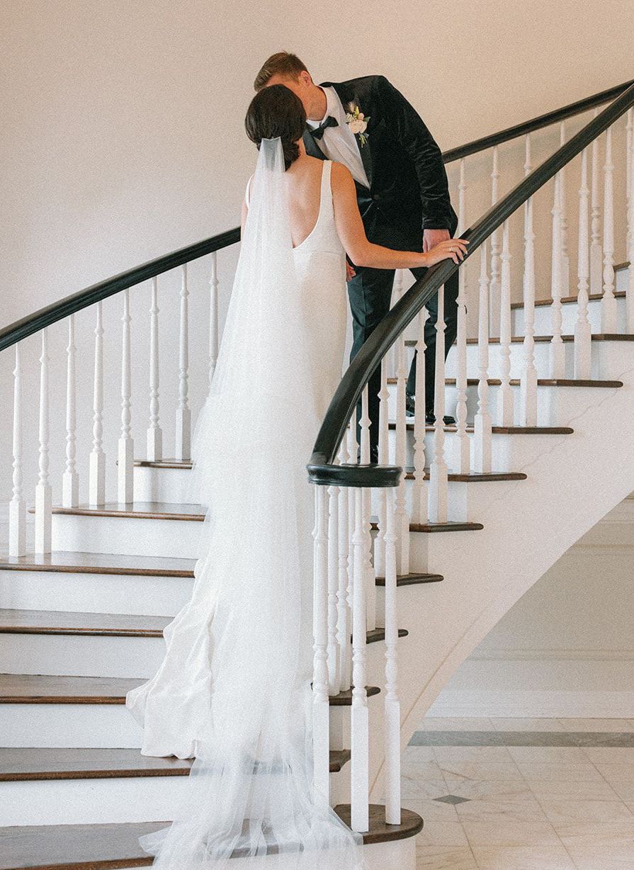 Bride and groom kiss on the grand stairwell at The Mansion at ColoVista for their southern styled shoot.