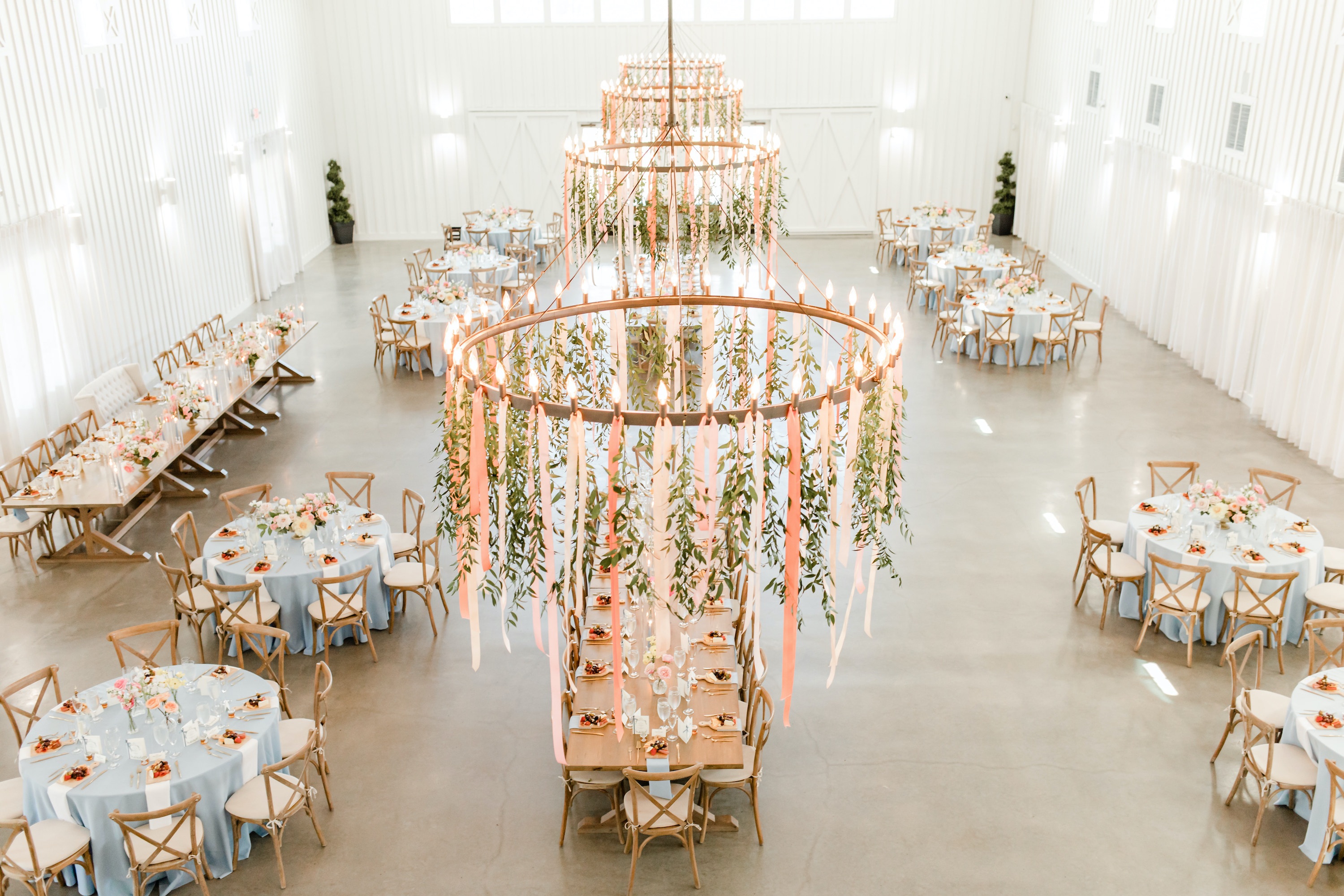 The chandeliers in the reception room have colorful streamers hanging from them with sunshine pouring into the room.