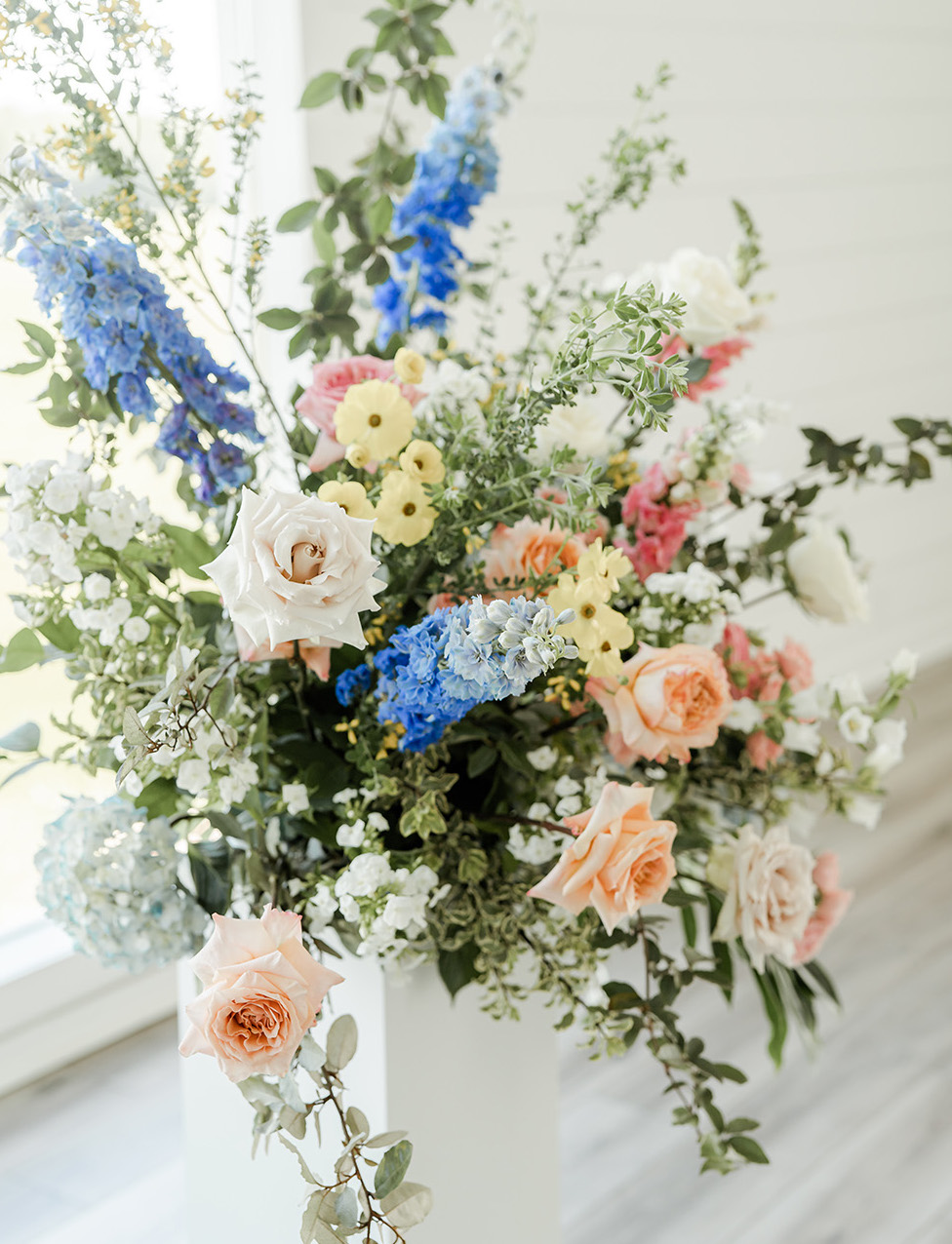 Vibrant flowers in blue, yellow and peach are designed in an arrangement on the altar.