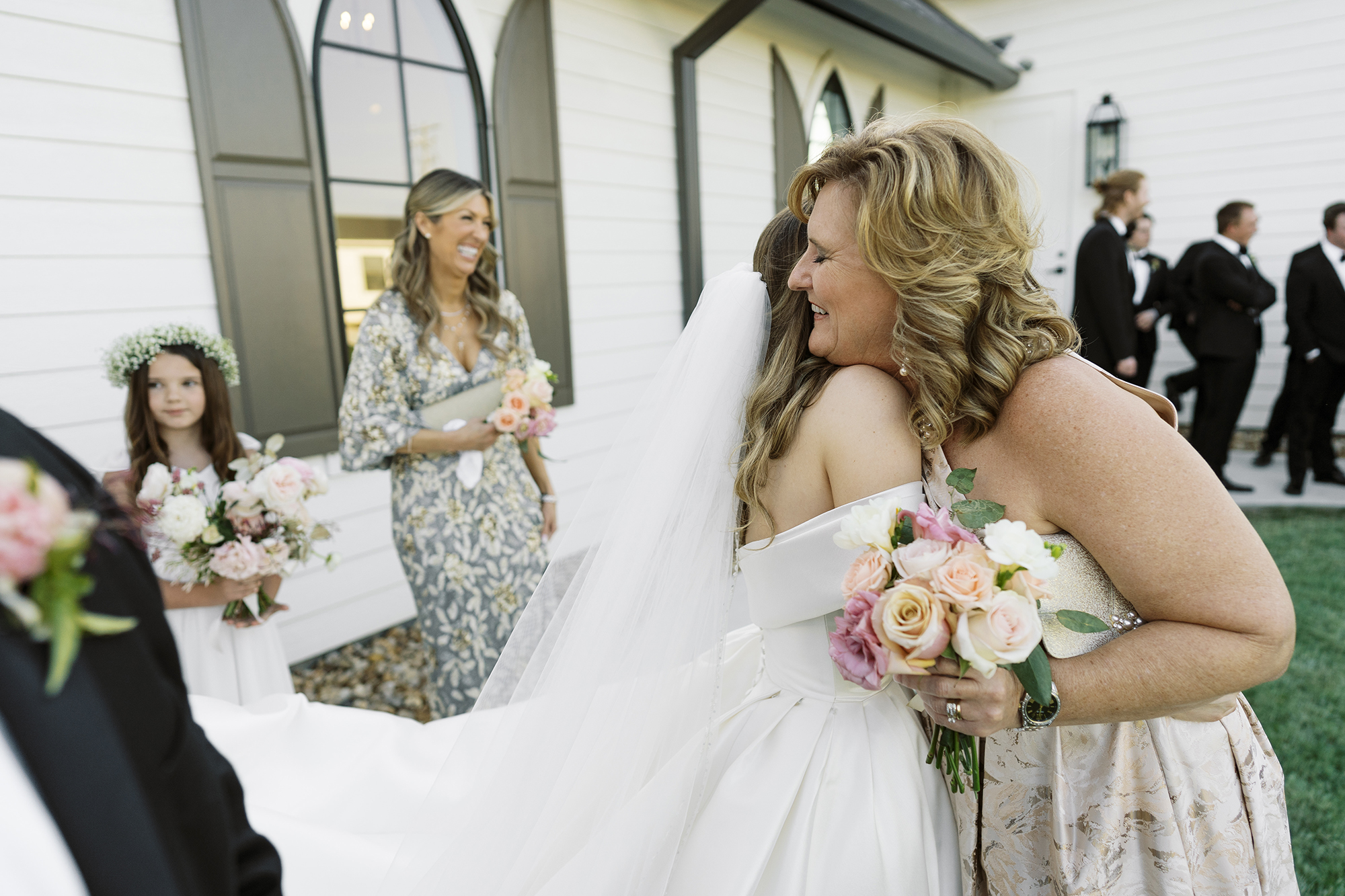 The bride hugs her husband's mom after the wedding, outside the chapel.