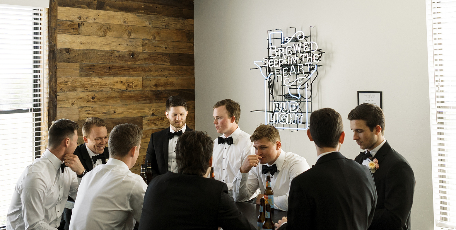 The groomsmen and the groom are drinking beers in the groom's suite.