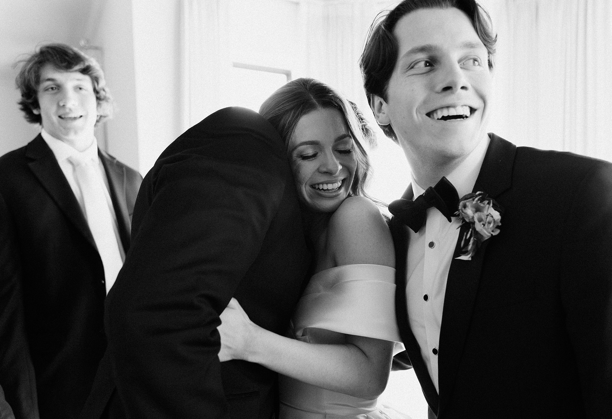 The brides hugs one of the groomsmen and smiles.