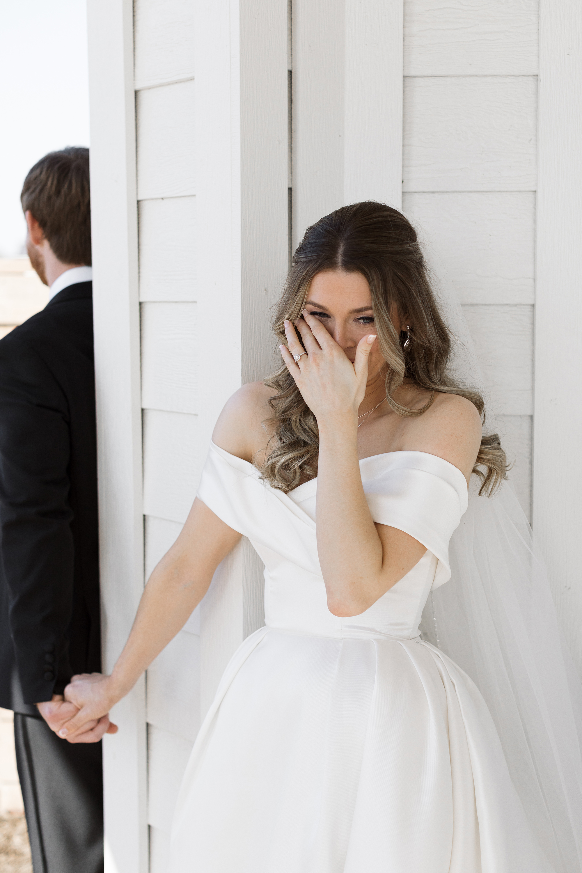 The bride and groom have their emotional first touch. The bride is wiping a tear from her eye.