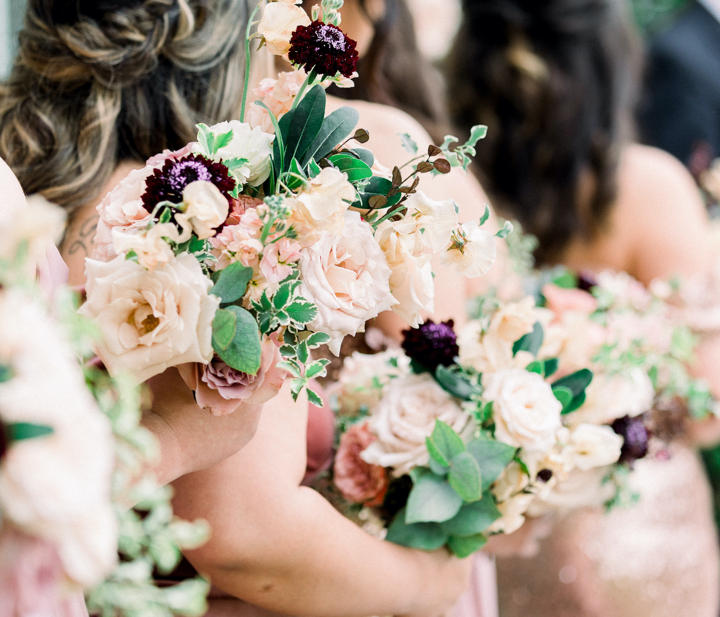 Bridesmaids holding purple, blush and ivory bouquets at an alfresco wedding ceremony at Texas Hill Country wedding venue, Ma Maison. 