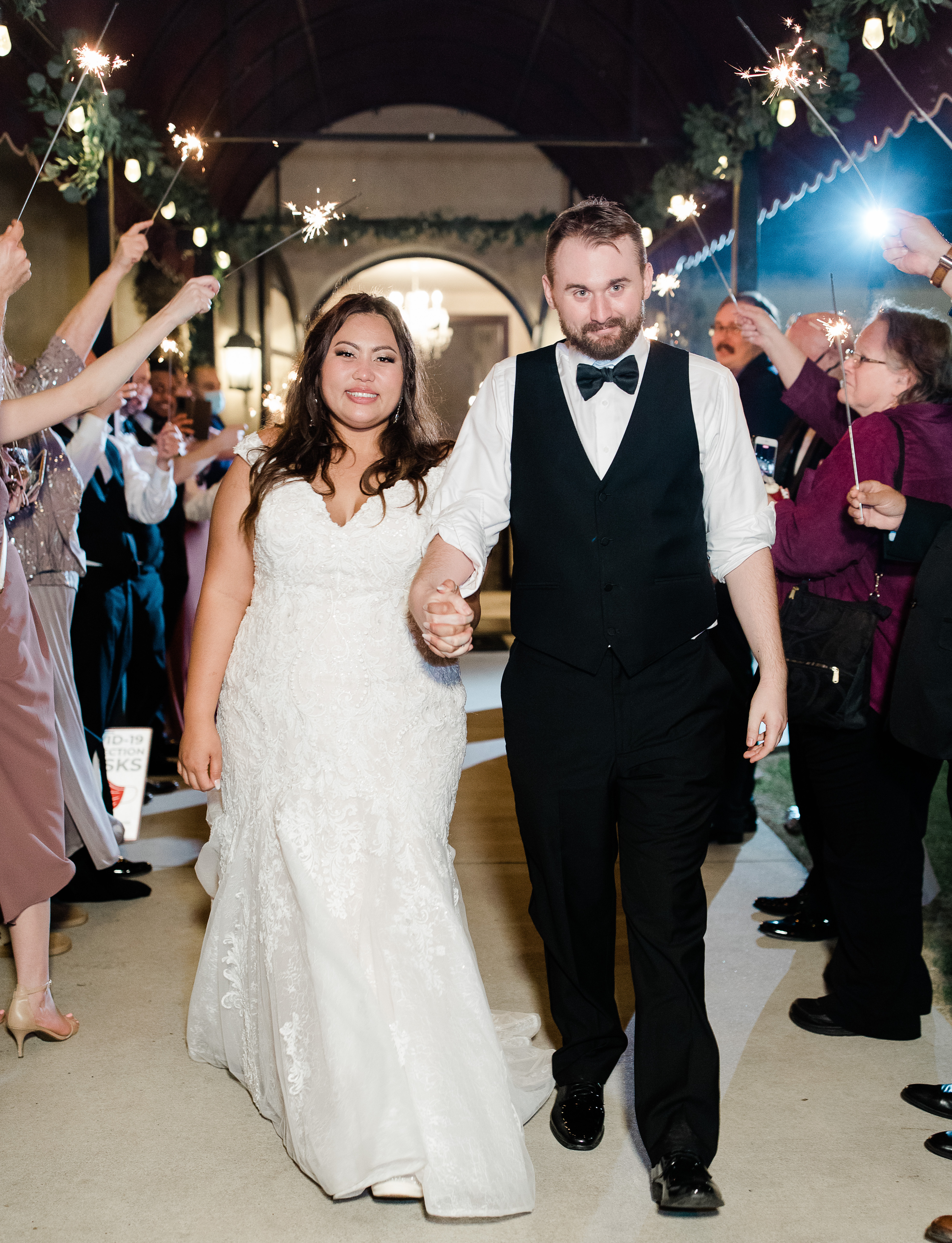 The bride and groom at their send-off where their guests hold sparklers.