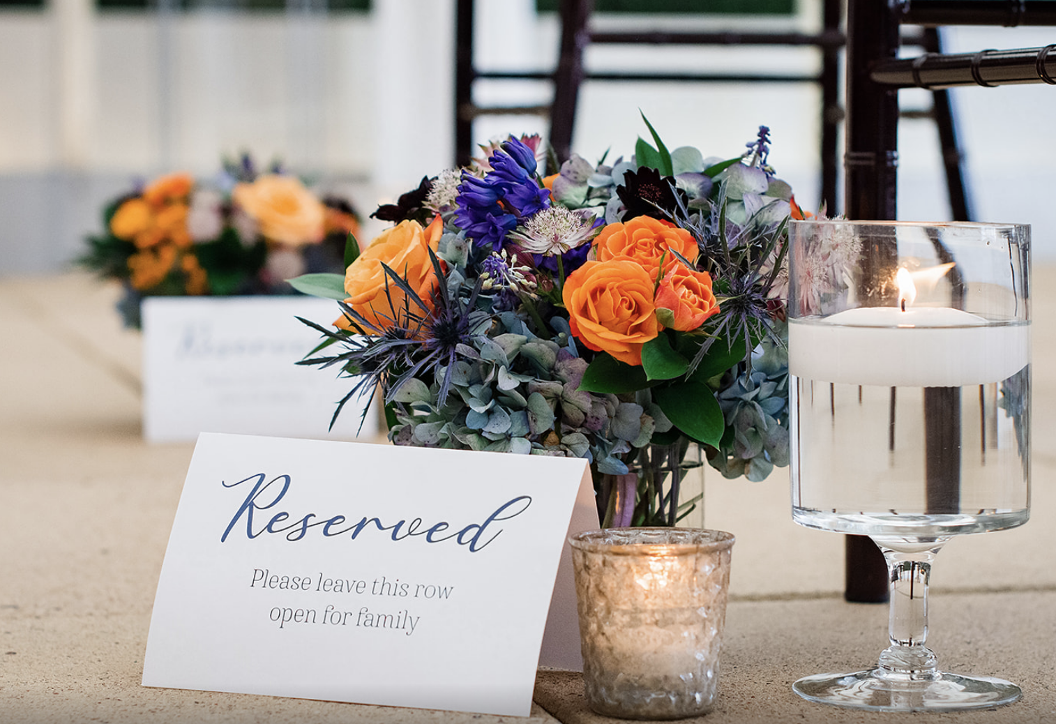 Floating candles and a mini arrangement are placed beside each row for the ceremony.