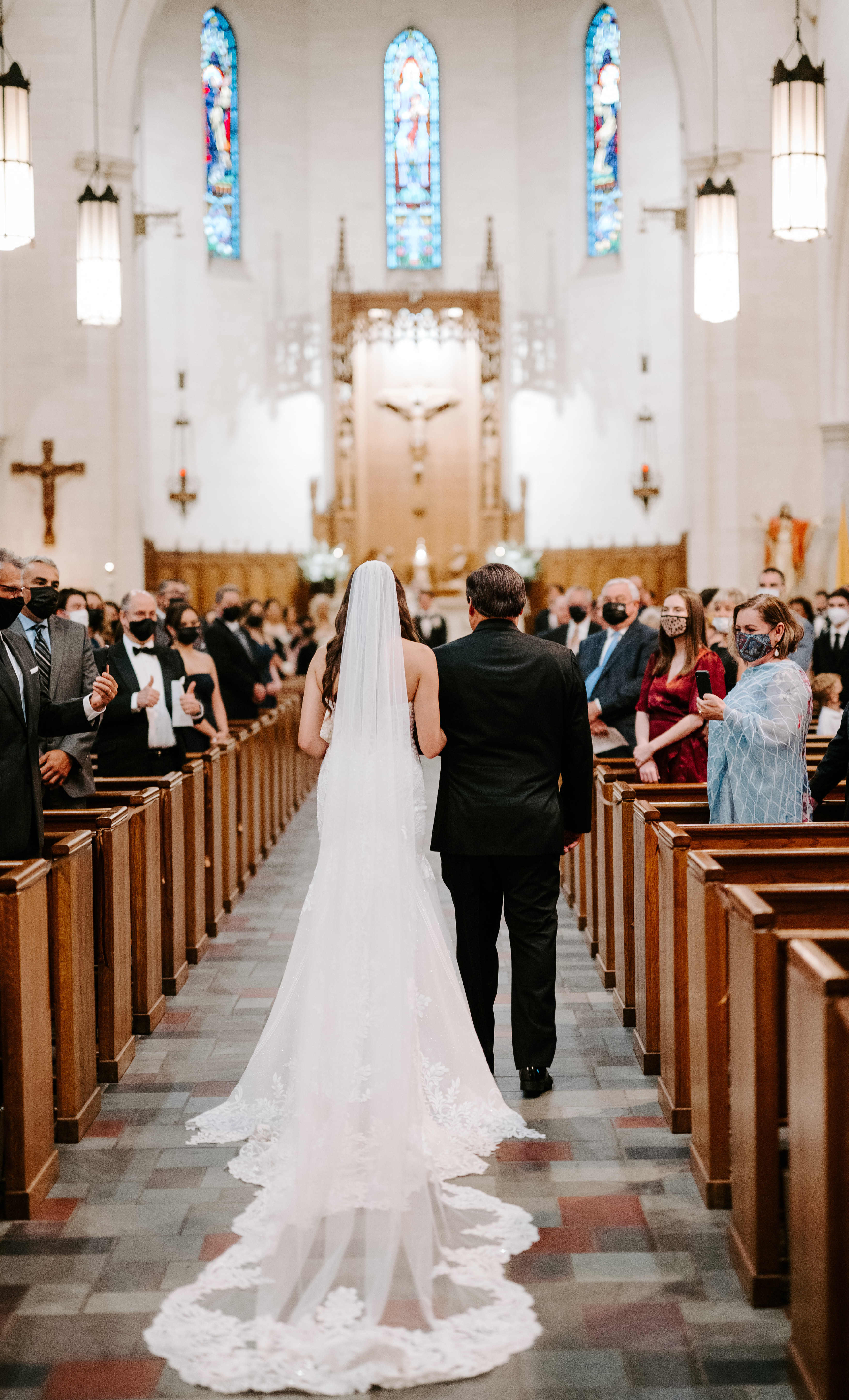 The bride and her father walk down the aisle to the altar.