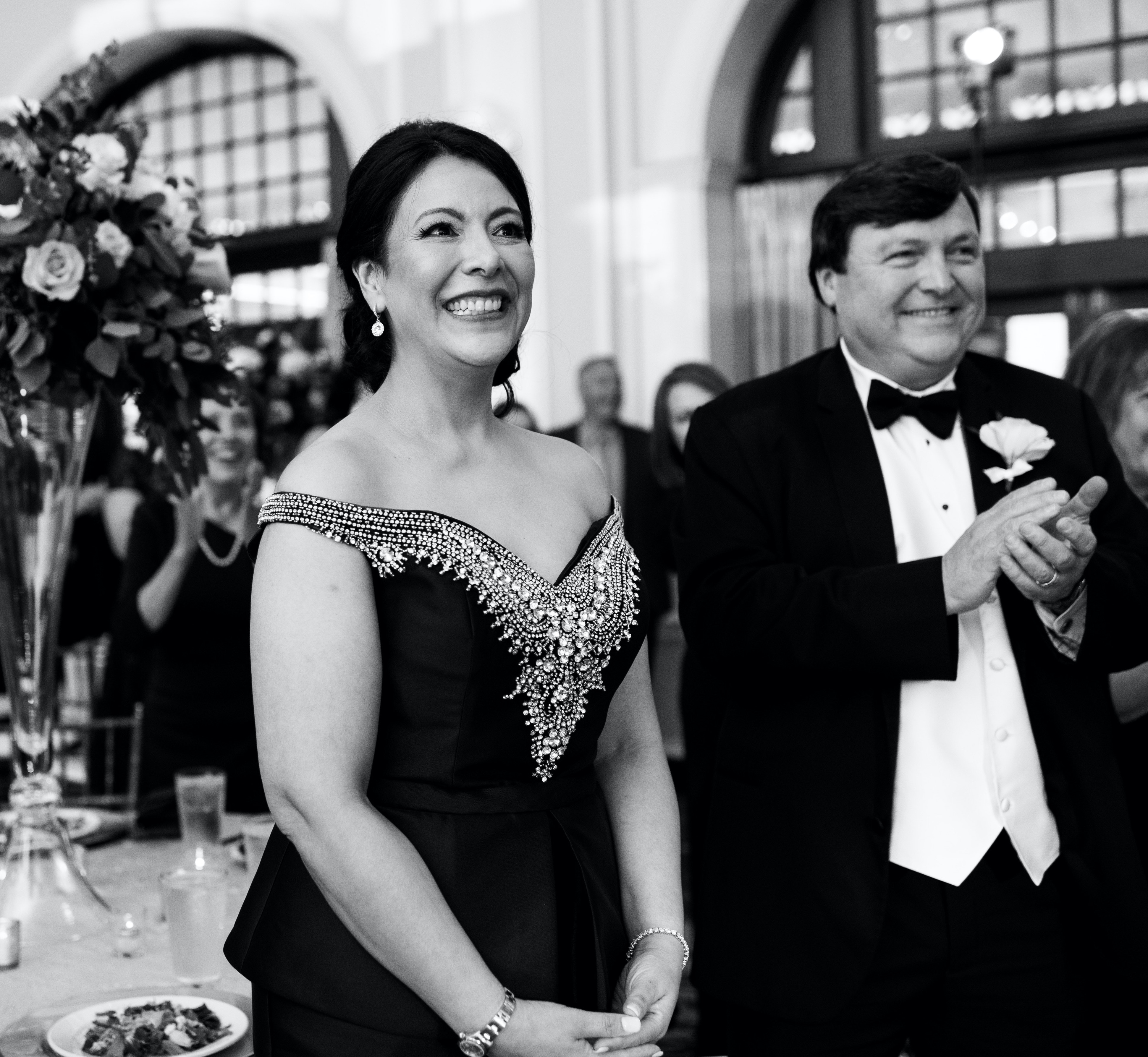 The bride's parents smiling at the bride and groom dancing.