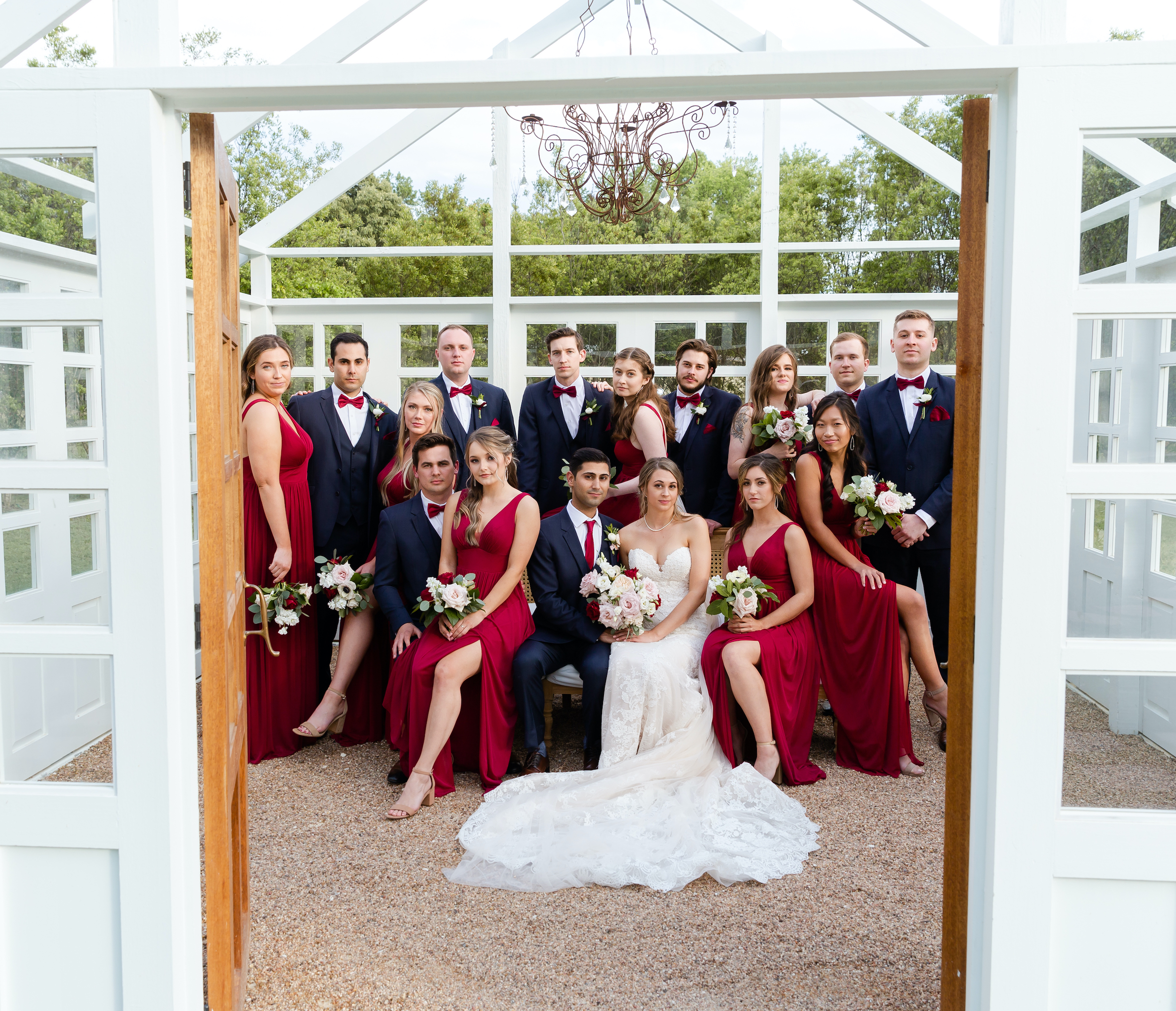 The bride and groom pose with their wedding party in the greenhouse.