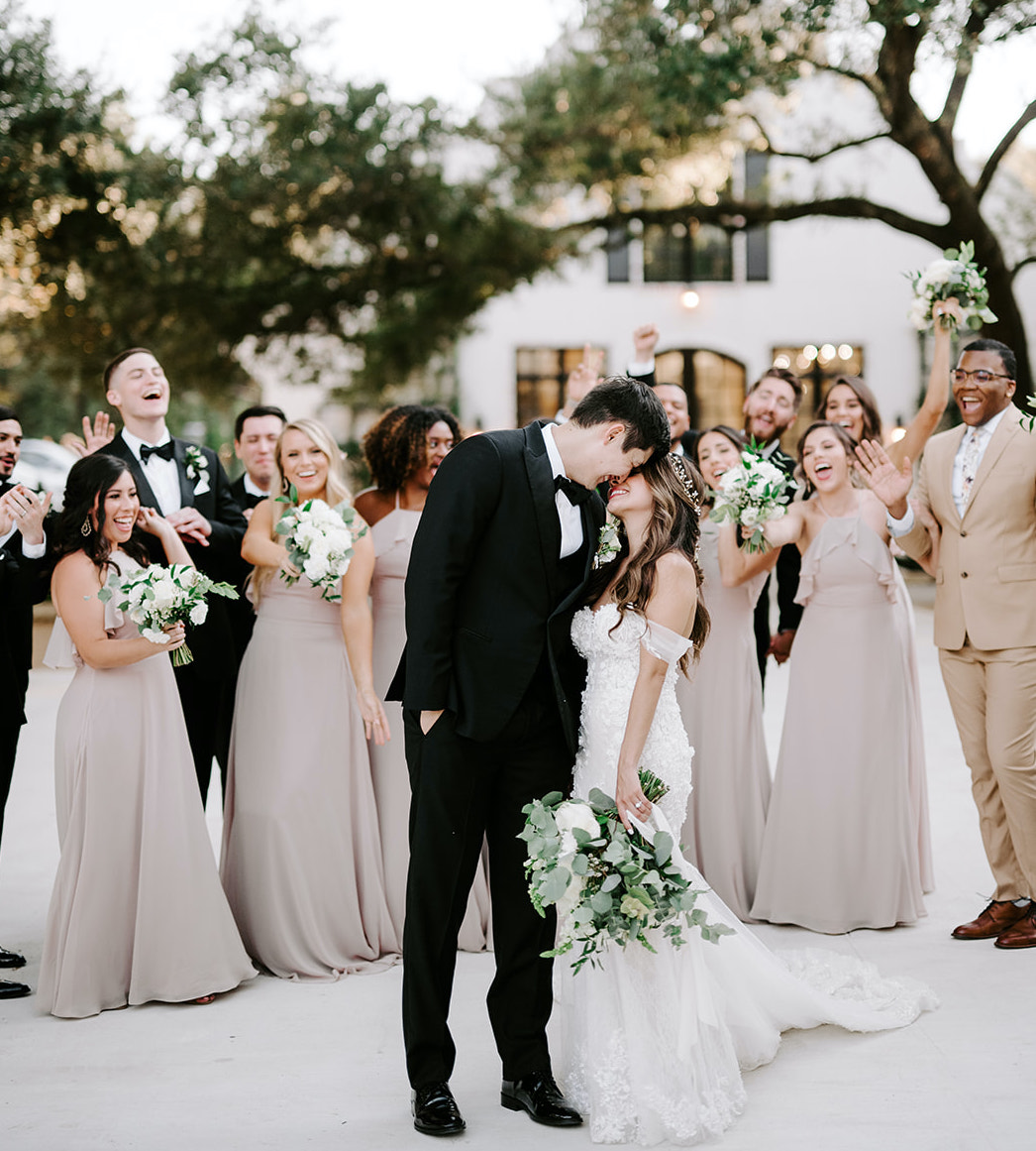 The bride and groom embrace in front of their wedding party outside of The Peach Orchard Venue.