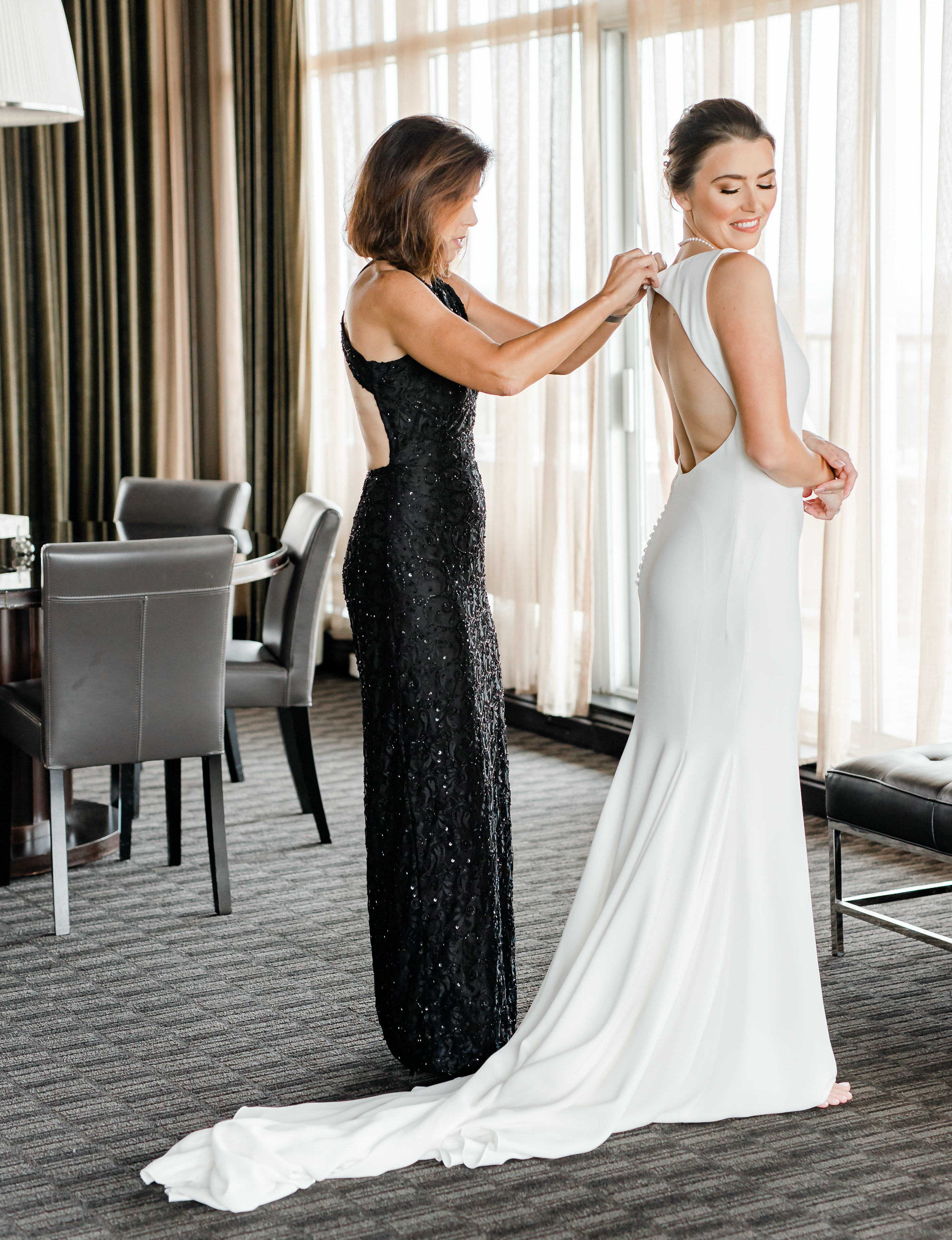 The mother of the bride helps her put her wedding dress on for her wedding in the museum district.