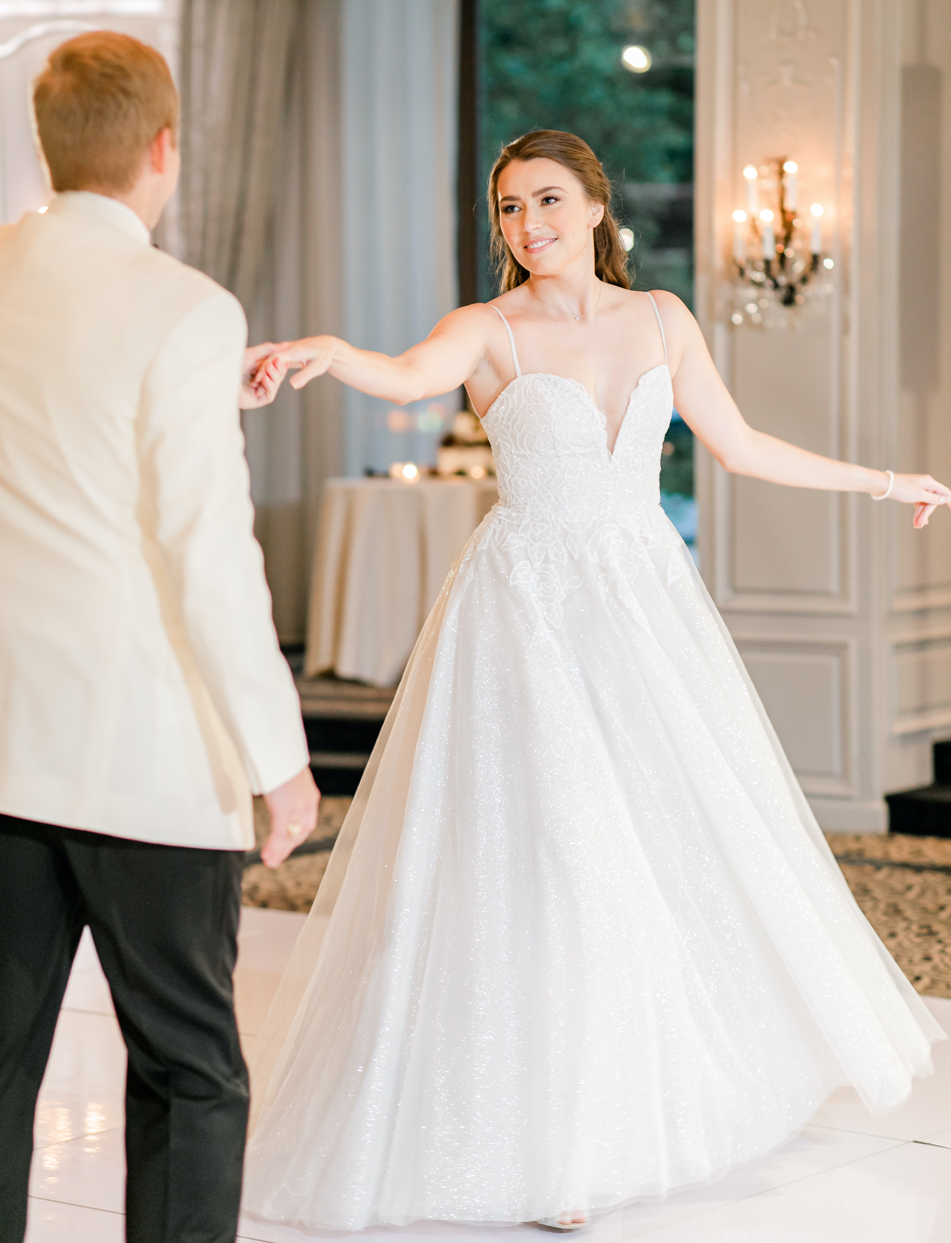 The groom twirls his bride in her sparkling gown at their wedding reception in the Houston museum district.