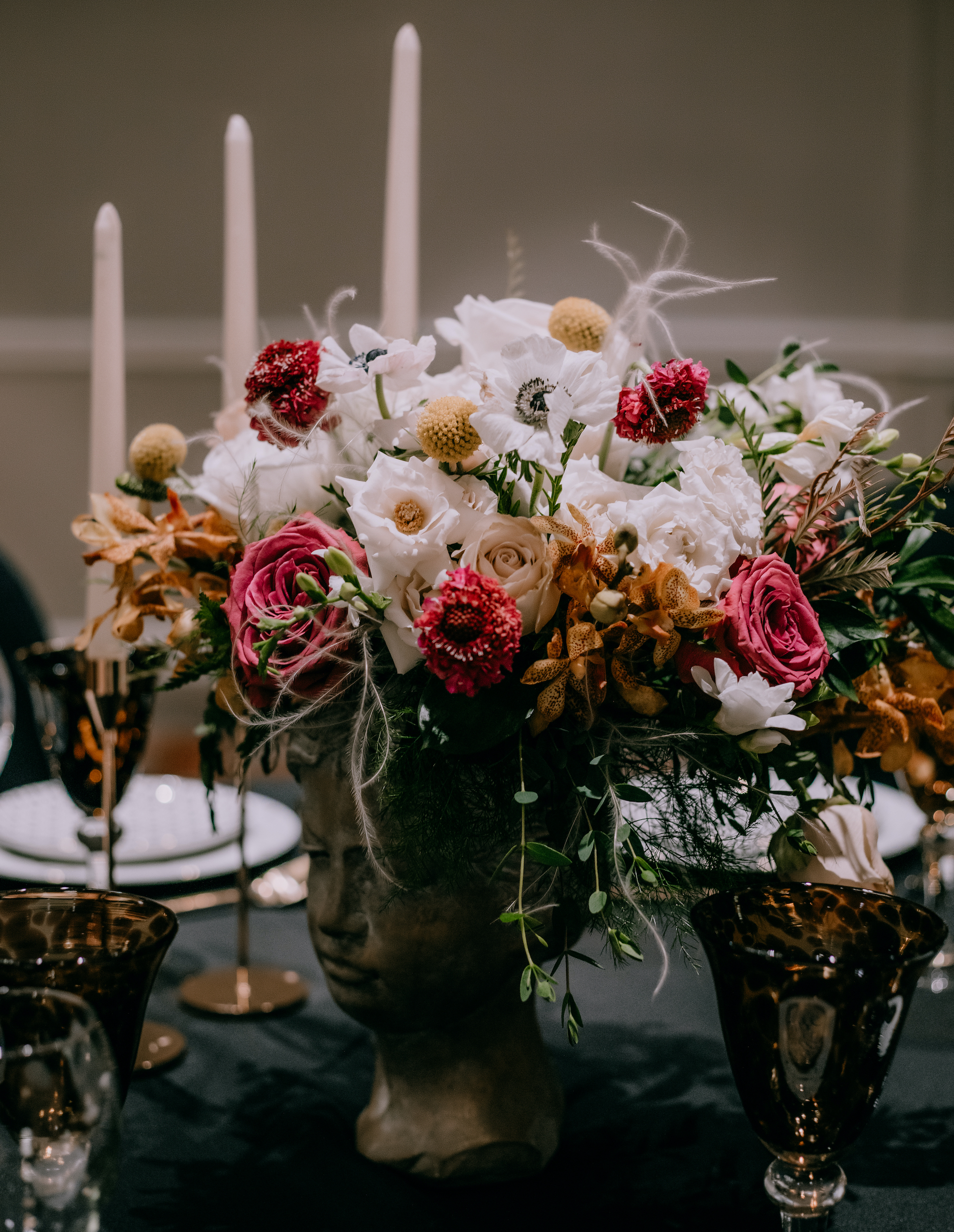 An up close photo of a reception dinner centerpiece that has yellow, white and magenta flowers.