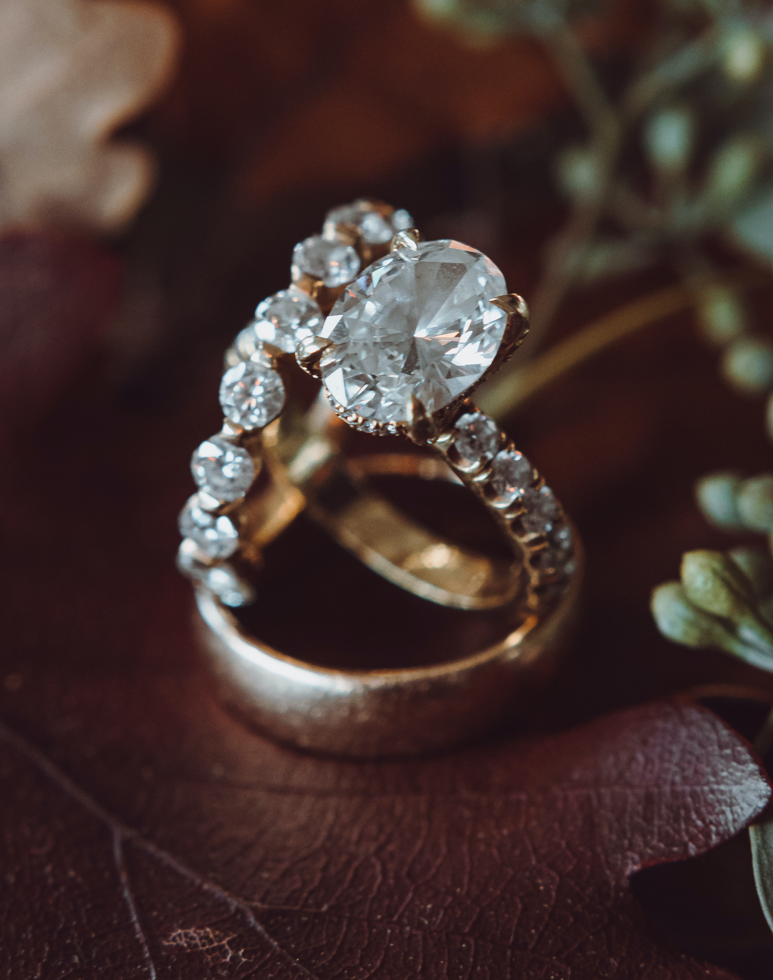 Diamond wedding band, oval wedding ring and gold wedding band sit atop a leather couch at a real wedding at wedding venue, The Astorian. 