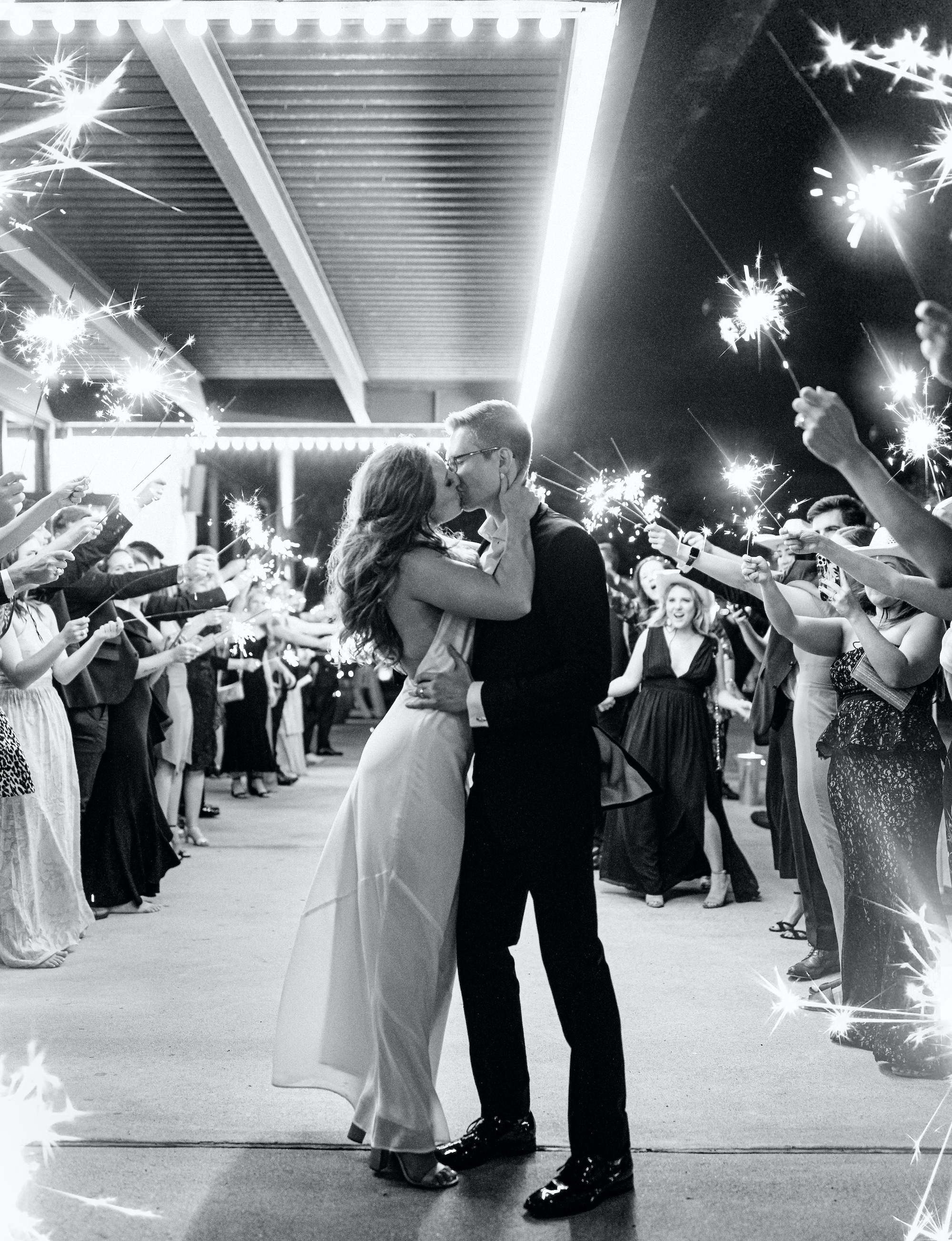 Bride and groom kiss during a sparkler send-off after their wedding at The Astorian in Houston, Texas.