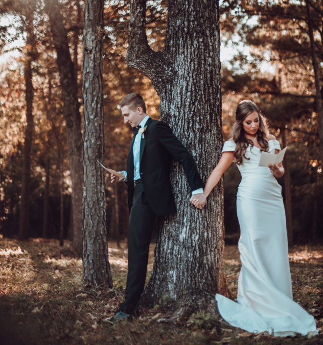 Bride and groom hold hands while they read their wedding vows to each other at an intimate wedding ceremony in autumn. 