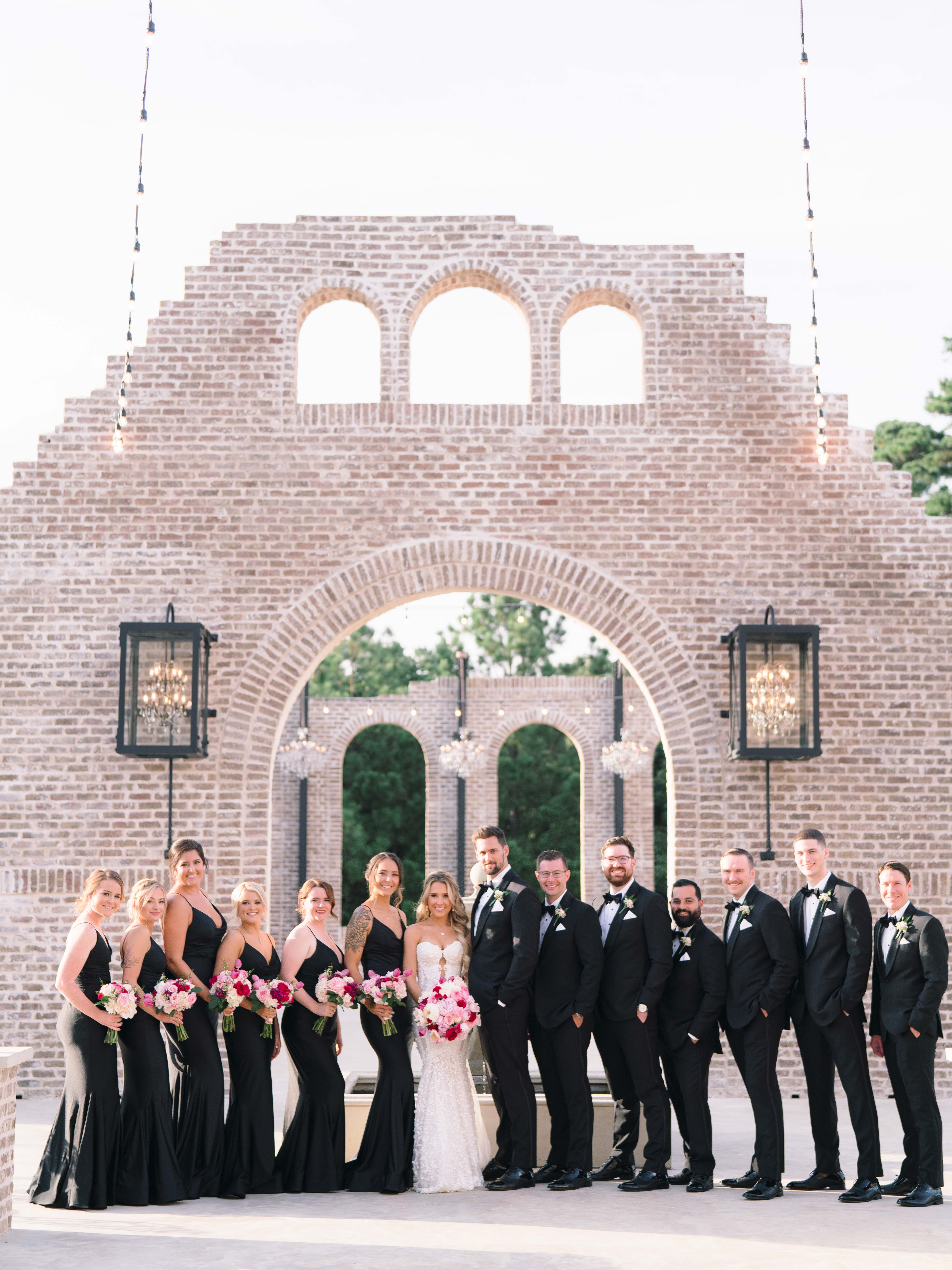 A bride and groom pose with their wedding party after their Summer Wedding With a Vibrant Palette of Pink.