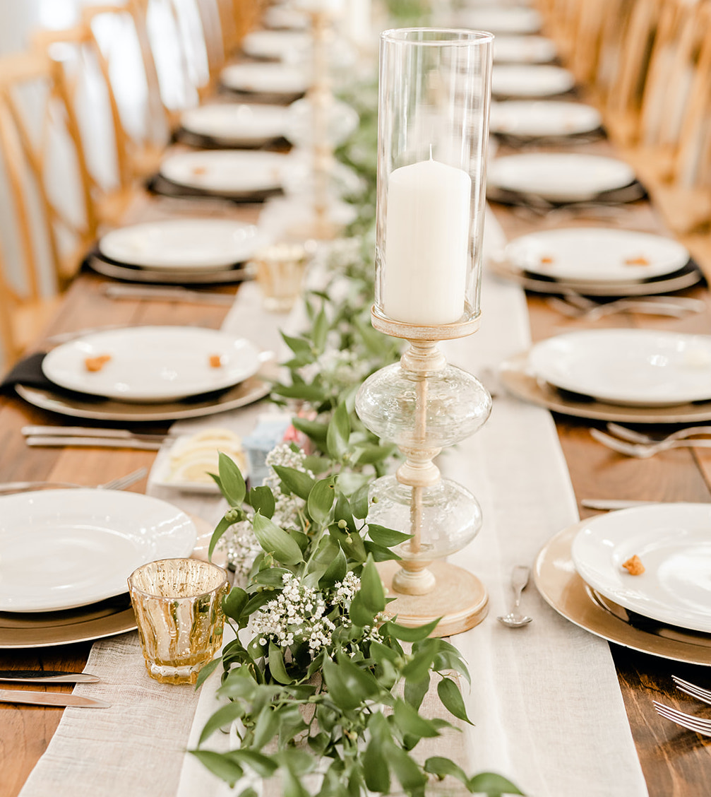 A wedding reception table decorated with greenery and baby's breath.