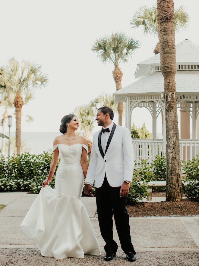 Bride smiles at groom in front of gazebo at The San Luis Resort, Spa and Conference Center. 