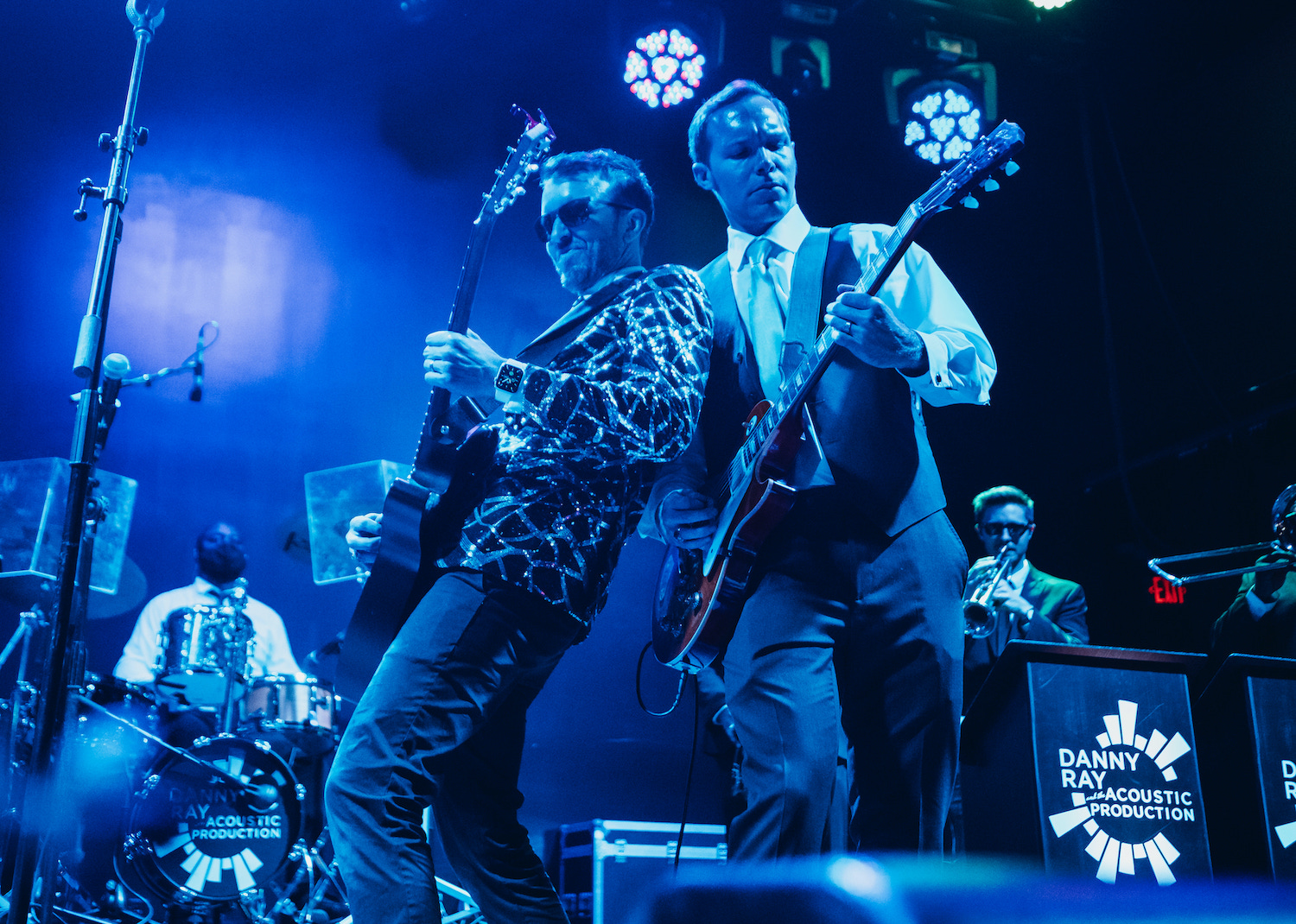 A groom gets on stage with the live performer, Danny Ray and the Atlantic Street Band, and plays electric guitar with him.